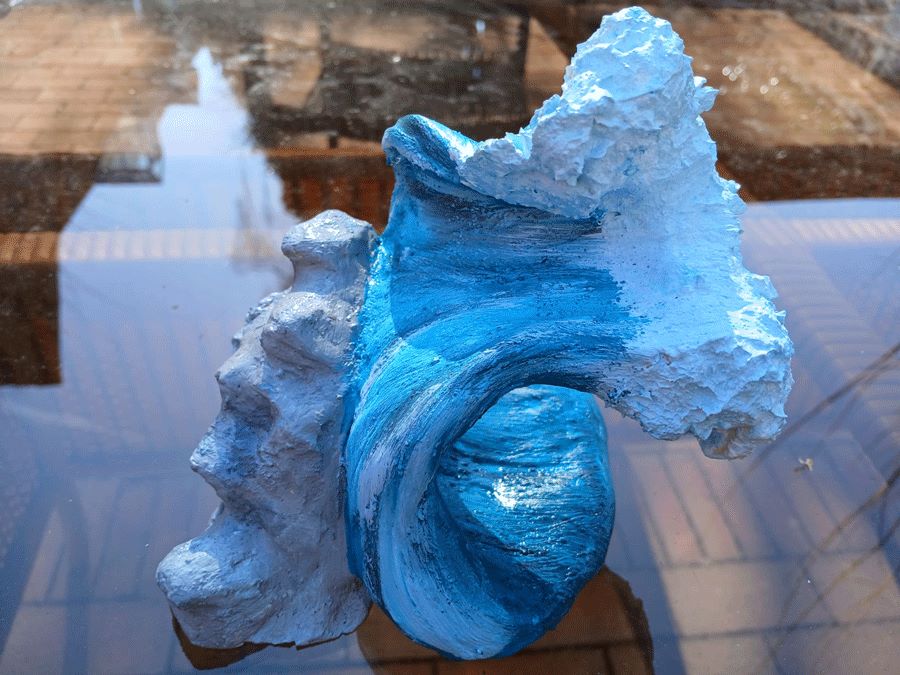 Fotografie einer Plastik, die aussieht, wie eine blaue Welle mit weißer Schaumkrone
